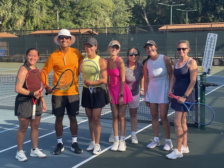 A women’s clinic lined up on court with their racquets