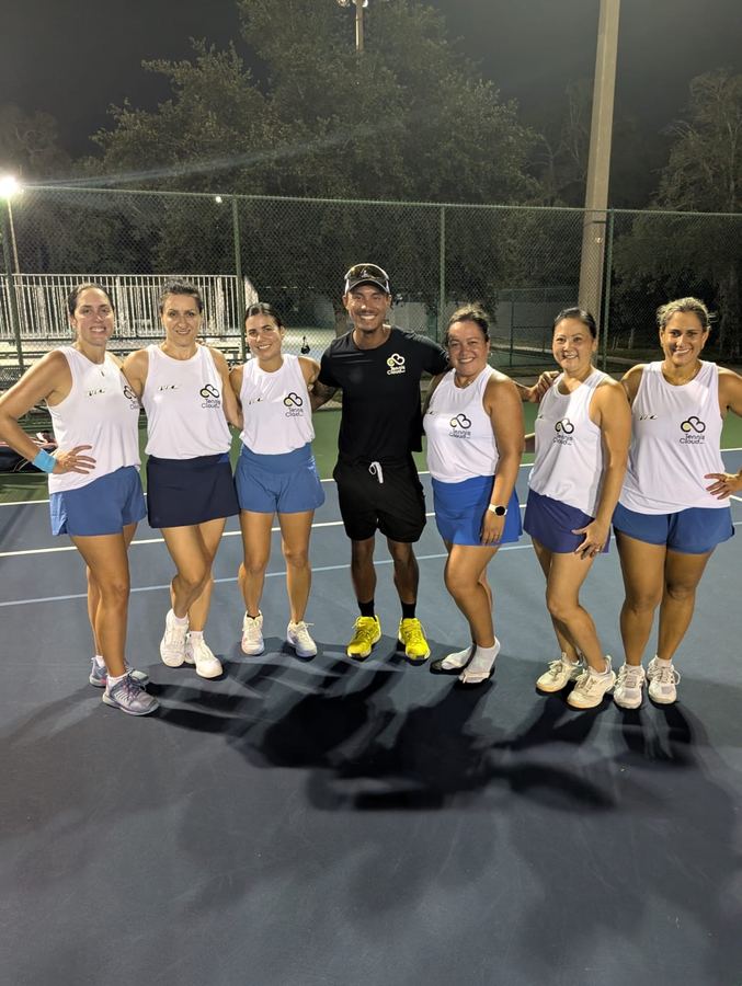 A team in matching shirts on court at night with Coach Liam